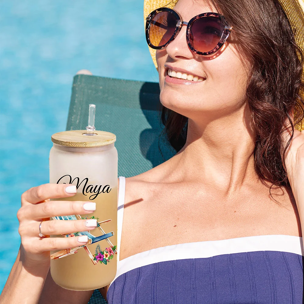 Bicchiere di vetro personalizzato smerigliato con nome, da 20 oz con coperchio in bambù e cannuccia. Ci sono tre disegno tra cui scegliere, occhiali da sole, sedia da spiaggia e infradito.